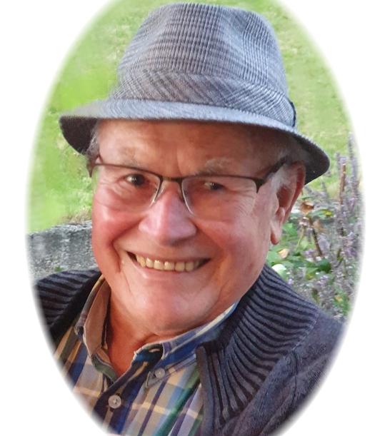 L&auml;chelnder &auml;lterer Mann mit Brille und Hut, Portr&auml;t vor gr&uuml;nem Hintergrund.