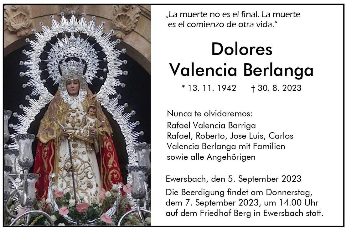 Statue einer heiligen Figur mit Krone, umgeben von Kerzenhaltern und Blumen, in einem religi&ouml;sen Kontext.