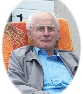 &Auml;lterer Mann mit Brille sitzt entspannt auf einem orangefarbenen Stuhl mit floralen Motiven im Freien.