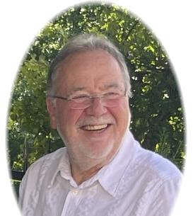 L&auml;chelnder Mann mit Brille und wei&szlig;em Hemd, umgeben von gr&uuml;nem Hintergrund. Ovaler Zuschnitt des Fotos.