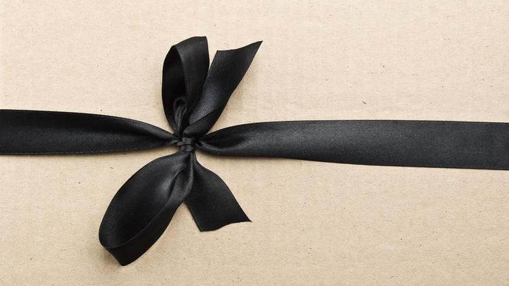 Schwarzes Satinband in Schleife auf braunem Geschenkpapier befestigt.