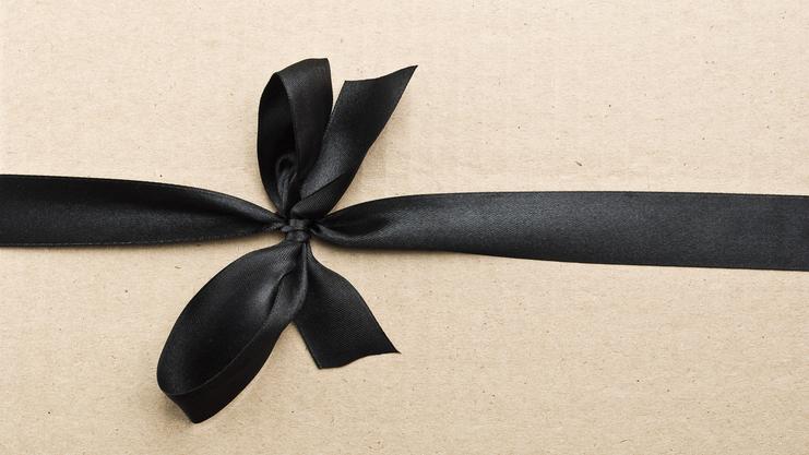 Schwarzes Satinband in Schleife auf braunem Geschenkpapier befestigt.